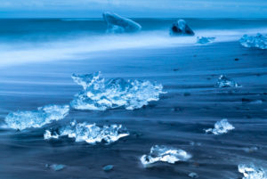Diamond Beach, pieces of ice on the beach with icebergs in the background Diamond Beach, pieces of ice on the beach with icebergs in the background